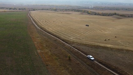 Kazakhstan, autumn, FJ Cruiser car drives through a mowed field, large panorama of a field with...
