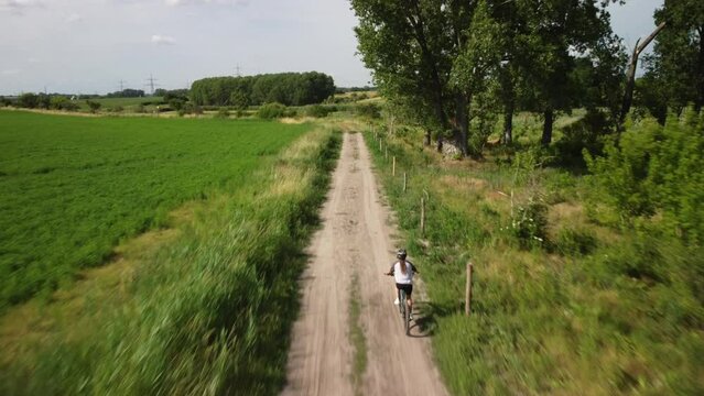Radfahrerin von hinten f&auml;hrt einen Feldweg entlang