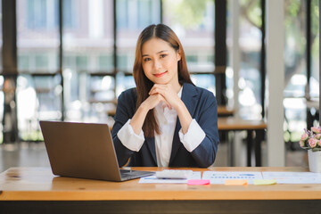 Obraz premium business woman or accountant who are using a calculator to calculate business data Accounting documents and laptop computer at the office business idea