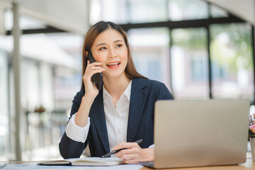 Young asian businesswoman beautiful charming smiling and talking on the mobile phone in the office