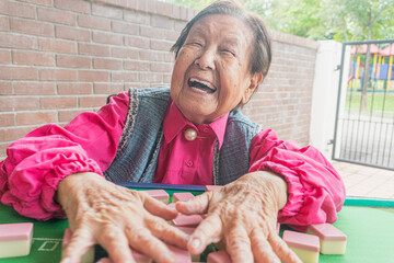 An old active elderly playing mahjong