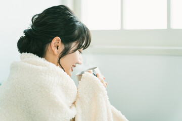 秋冬の寒い日にホットドリンクを飲むアジア人女性（寒い・冷え性）
