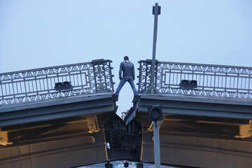 Russia. Saint-Petersburg. A man stands on the divorced Blagoveshchensk Bridge. - obrazy, fototapety, plakaty