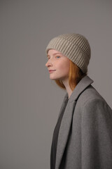 young girl model in beige hipster hat and coat isolated on light background. Product photo mockup for fashion brands and marketplaces, woolen cap, turkish textiles.