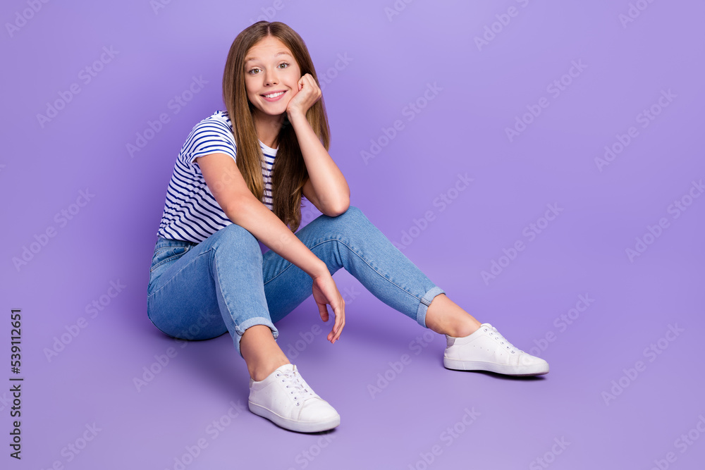 Poster full length photo of nice positive girl wear striped t-shirt sitting on floor hand on cheekbone isol