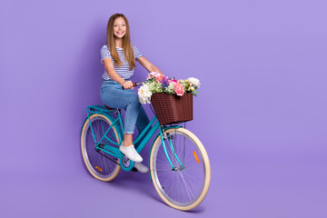 Full length photo of optimistic satisfied nice girl dressed striped t-shirt jeans riding bicycle isolated on purple color background