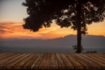 Fototapeta na wymiar Wooden table and blur of beauty, sunset sky, and mountains as background.