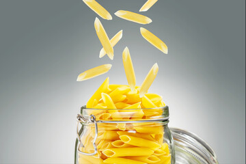 Pasta penne in glass jar and falling penne pasta.