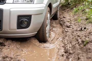 Modern hatchback car driving on bad dirt road with many puddles. Countryside road in terrible...