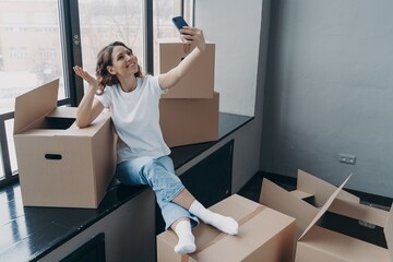 Girl blogger greeting followers in social network, doing overview of new apartment on moving day