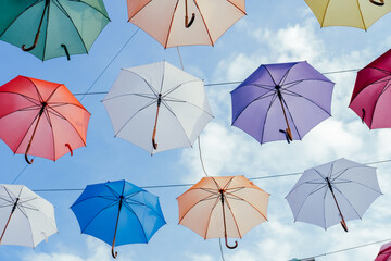 Many colorful umbrellas background. Opened umbrellas in the sky. Urban decoration. Bottom view.