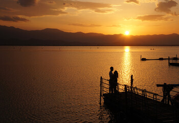 couple standing by the river at sunset