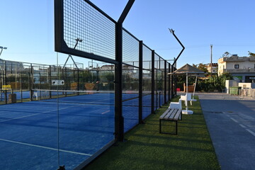 View on enclosed court for padel with construction created by mesh and the glass back walls. Padel...