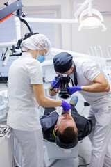 A young dentist takes a picture of the patient's teeth. The assistant helps the doctor. Dental...