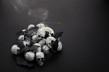 Halloween concept - black bats and skulls on black background.