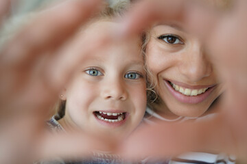 Adopted daughter, mom showing heart gesture together, symbol of love, care, support. Happy adoption