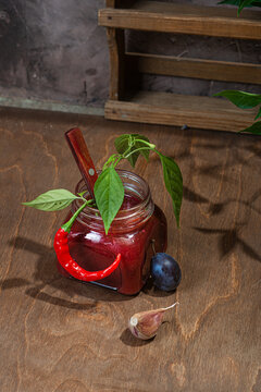 Plum sauce with hot pepper, garlic on a wooden table