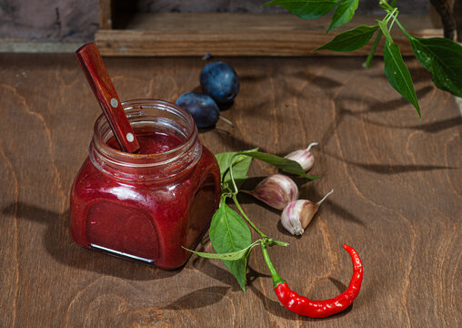 Plum sauce with hot pepper, garlic on a wooden table
