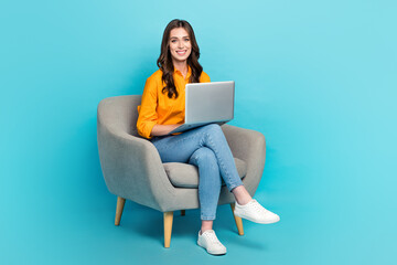 Full length portrait of positive nice person sit chair use wireless netbook isolated on blue color...