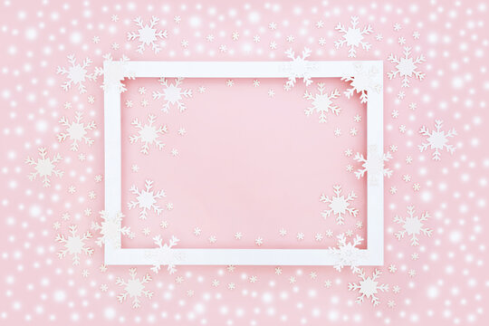Christmas snowflake and snow background border with white frame. Festive abstract minimal pastel pink composition with decorations for the holiday season.