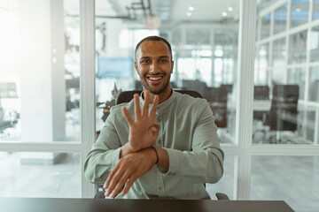 African businessman using sign language while talking online with client sitting in office