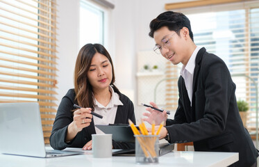 Young start up business people discussing information on document and using laptop at office.