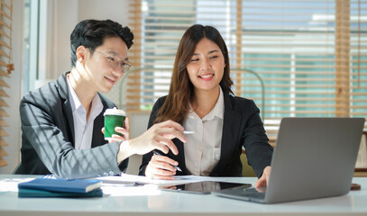 Smiling young businessman explaining online information to his colleagues.