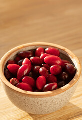Fresh ripe dogwood berries in bowl on wood table, closeup