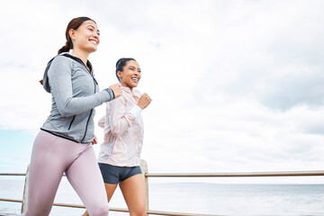 Friends, women and running by ocean, sea or promenade for wellness, fitness and health. Diversity, exercise and happy girls out for a run, cardio workout or training together outdoors by seashore.