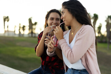 A beautiful lesbian young couple embraces and holds a rainbow flag. Girls drinking juice. LGBT community