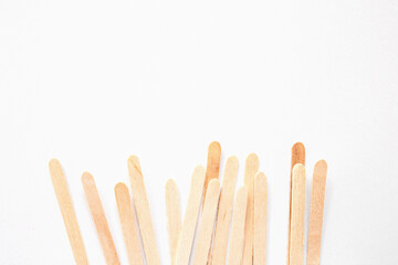 Materials for depilation of eyebrows and delicate areas. Wooden sticks lie on a white background. View from above