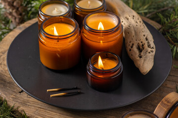 Soy candles burn in glass jars. Comfort at home. Candle in a brown jar. Scent and light. Scented handmade candle. Aroma therapy. Christmas tree and winter mood. Cozy decor. Festive decoration
