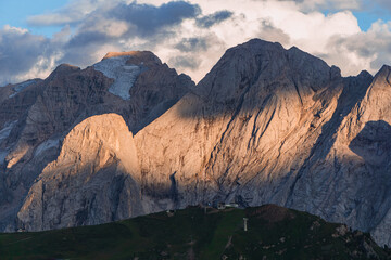 Marmolada, one of the symbolic mountains of the Dolomites and Val di Fassa with the evening lights, near the town of Canaze, Italy - August 2022.
