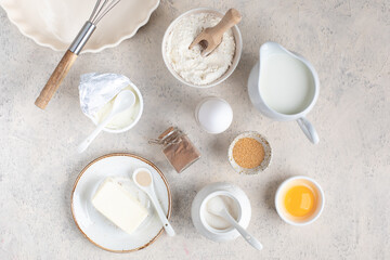 The concept of home baking. Ingredients for making dough, cake, cupcakes: eggs, flour, butter, cinnamon, milk, sugar on a light background.