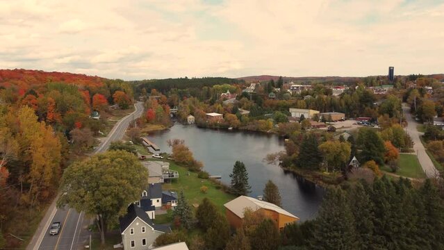 Aerial drone flyover Burk's Falls along ryerson centre road, a small charming village surrounded by deciduous trees, colored in beautiful vibrant autumn palette, parry sound District, Ontario, Canada.