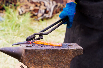 Blacksmith lays down a hot iron on anvil for forging