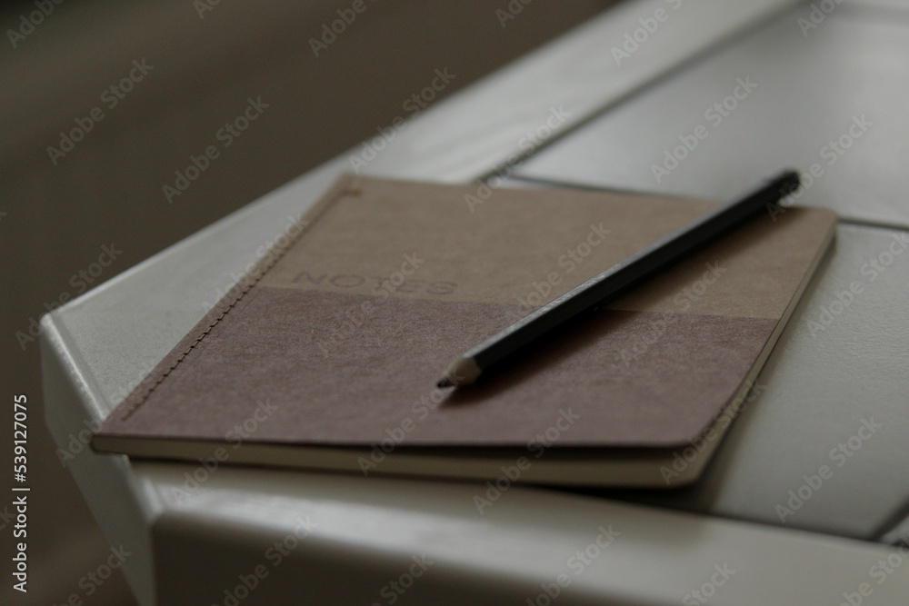 Poster brown notebook with a pencil on a table - concept of idea generation