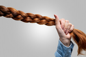 Woman's hand holding a braid of hair