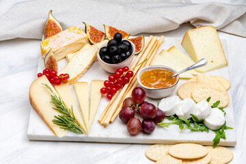 cheese plate with soft and hard cheeses brie, camembert, pecorino, goat cheese with jam olives and grissini and crackers. Italian and French cheeses