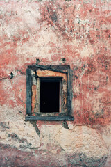 Pink weathered plaster wall with neglected small window.