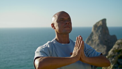 Athlete practicing yoga ocean view. Focused man meditating in namaste position