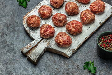 Raw meatballs, minced pork meat on white plate dark background. Culinary, cooking concept. Food recipe background. Close up