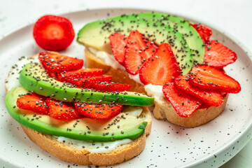 avocado toast with strawberries, soft cheese and chia seeds on a light background. healthy Breakfast or lunch. Keto diet. Food recipe background. Close up