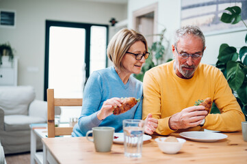 Senior couple eating breakfast at home and spending morning together