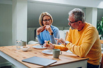 Senior couple eating breakfast at home and spending morning together