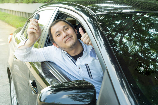 Closeup Portrait Young Middle Man Smiling Buyer Sitting In His New Black Car Showing Key Outside Dealership Office. Personal Transportation. Auto Purchase Concept. Handsome Guy Showing His Key Car.