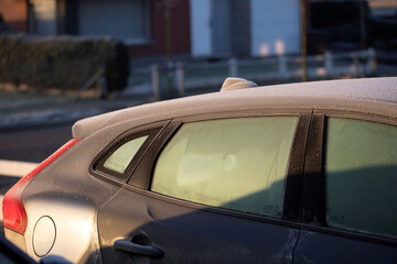 A portrait of the side of a car with frozen side windows during winter. The ice first needs to melt or be removed before the driver can safely start the journey.