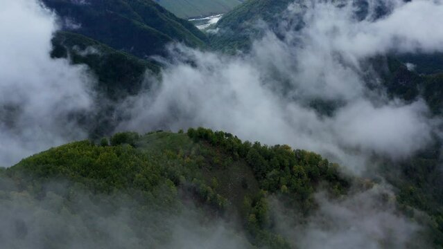 A forested hill surrounded by fast-moving clouds, National Park Thet, Albania