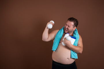 Funny fat man with a blue towel around his neck and dumbbells in his hands. Motivation for sports....