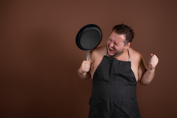 Funny plump man with a frying pan in his hands. Cute chef on a brown background. Preparation of a dietary menu.